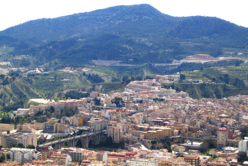 Vista de Alcoy con el puente, los edificios del casco urbano y la sierra al fondo