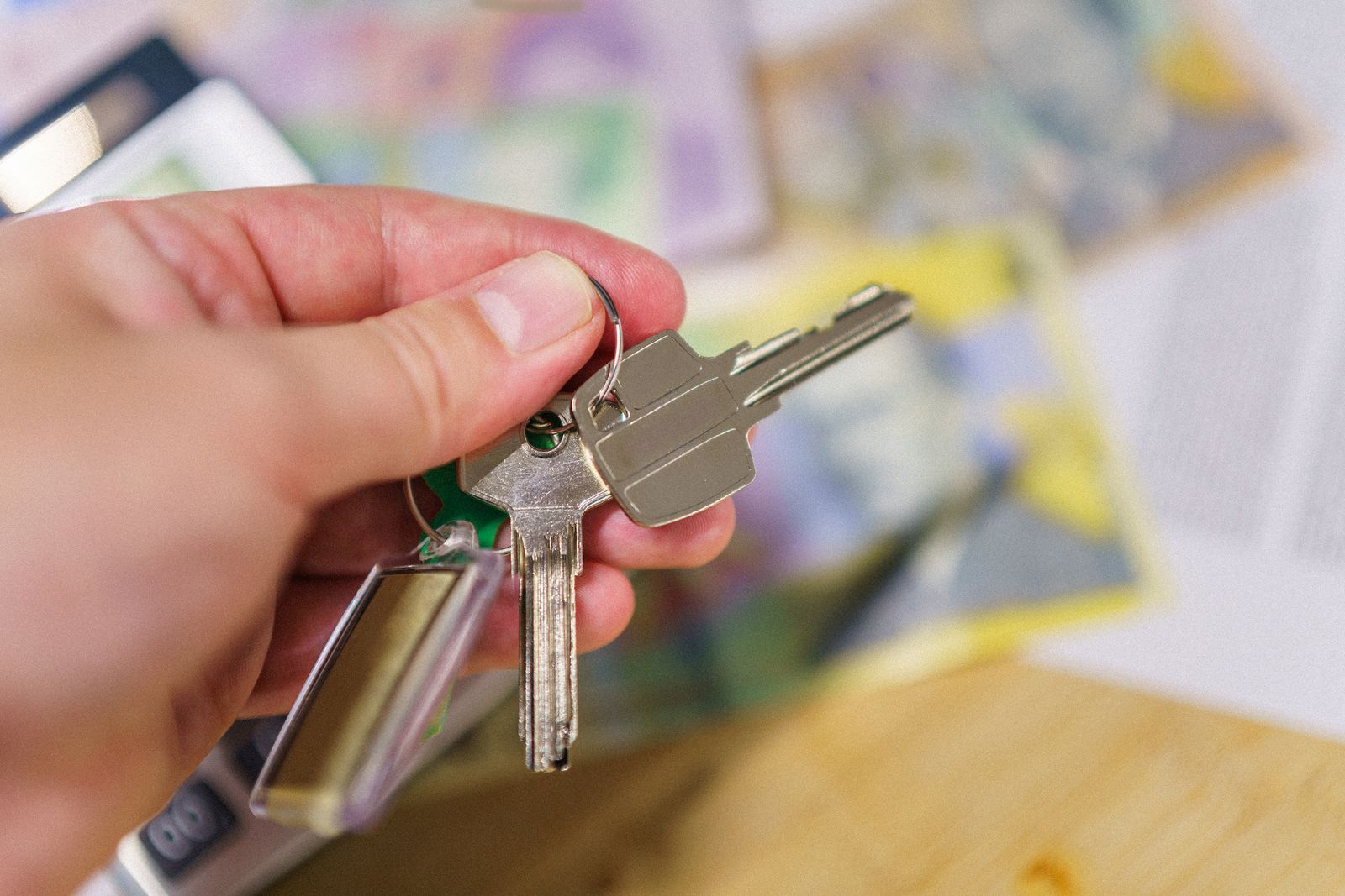 Llaves de una vivienda en la mano junto a documentos de alquiler