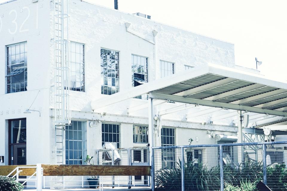 Edificio industrial blanco con marquesina y grandes ventanales, imagen de un parque empresarial